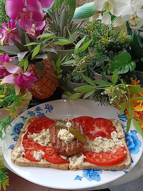 Sándwich con hamburguesa vegana, tomate y salsa tártara